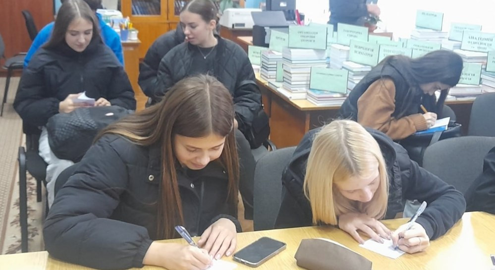 Студенти за столом працюють в науковій бібліотеці
